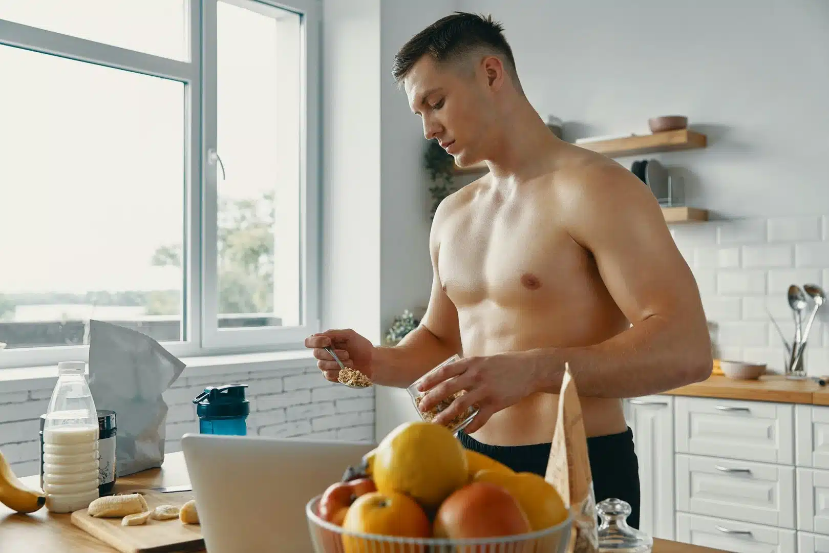 Young fit man preparing healthy food while standing at the kitchen